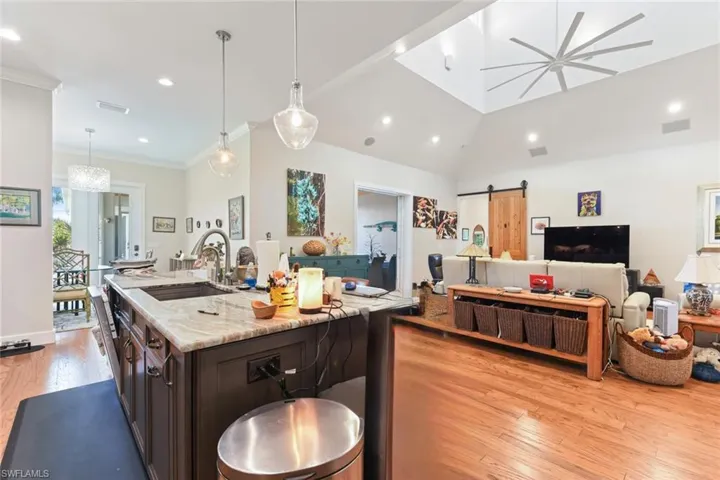 Kitchen featuring a barn door, a sink, light wood finished floors, open floor plan, and dark brown cabinetry