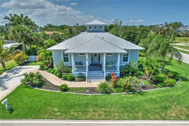 View of front of house with covered porch, a front lawn, and metal roof