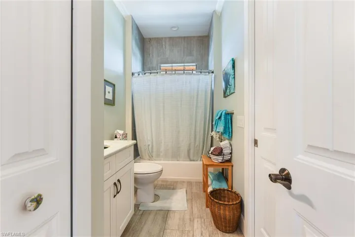 Full bathroom with toilet, vanity, shower / bathtub combination with curtain, and wood finished floors