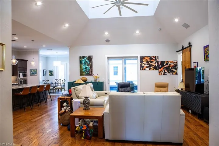 Living room featuring lofted ceiling, a barn door, wood finished floors, plenty of natural light, and a ceiling fan