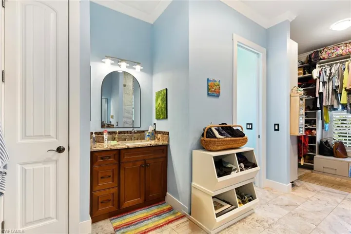 Bathroom with crown molding, vanity, a walk in closet, and baseboards