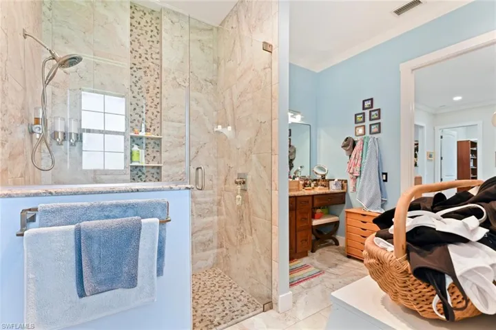 Bathroom featuring a shower stall, ornamental molding, marble look tile flooring, and vanity