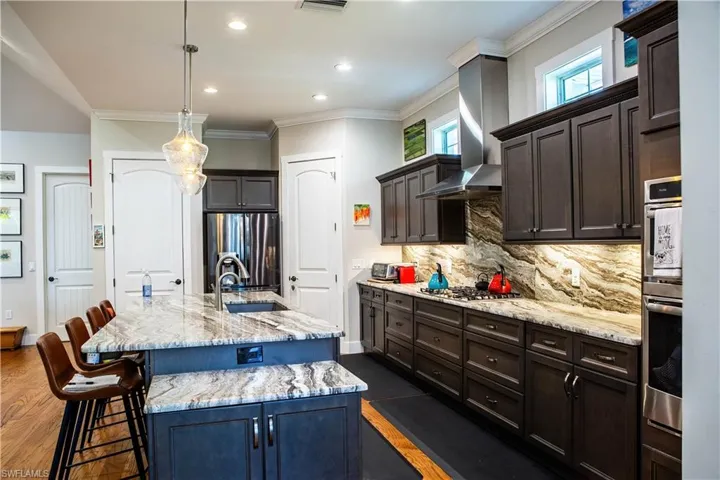Kitchen featuring a sink, stainless steel appliances, a kitchen breakfast bar, tasteful backsplash, and light stone countertops