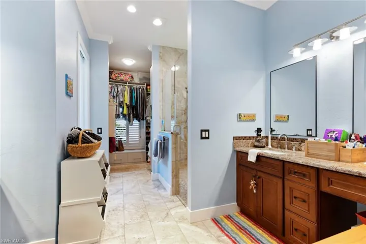 Bathroom with a stall shower, ornamental molding, vanity, a spacious closet, and marble finish floors