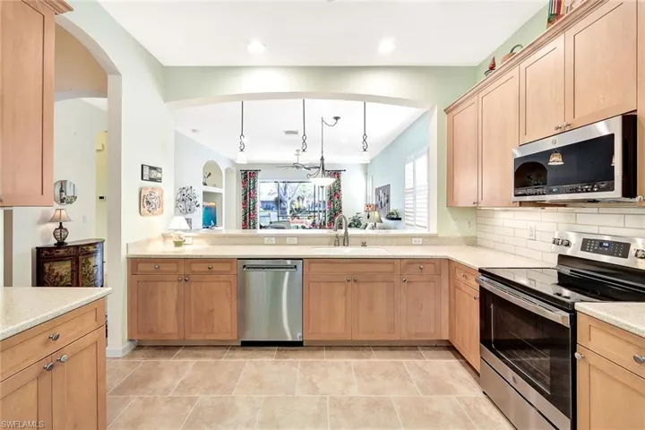 Kitchen with appliances with stainless steel finishes, sink, hanging light fixtures, and light brown cabinets