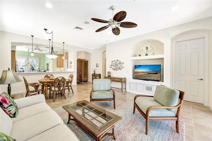 Living room featuring light tile patterned floors, built in shelves, and ceiling fan