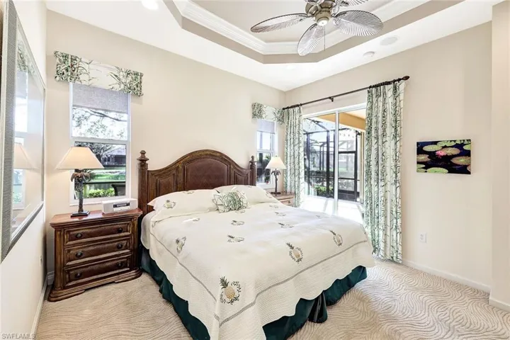Carpeted bedroom featuring a raised ceiling, crown molding, access to outside, and ceiling fan
