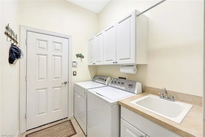 Laundry room featuring cabinets, washing machine and dryer, and sink