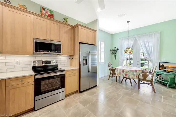 Kitchen featuring appliances with stainless steel finishes, decorative light fixtures, light brown cabinets, and backsplash