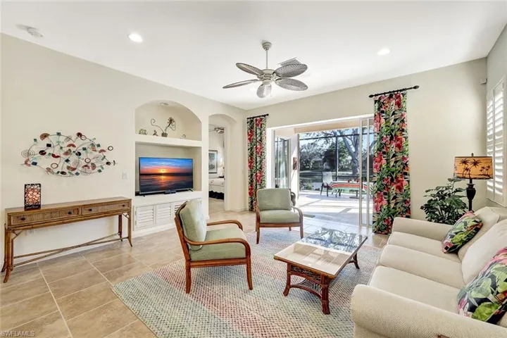 Living room with built in shelves, ceiling fan, and light tile patterned flooring