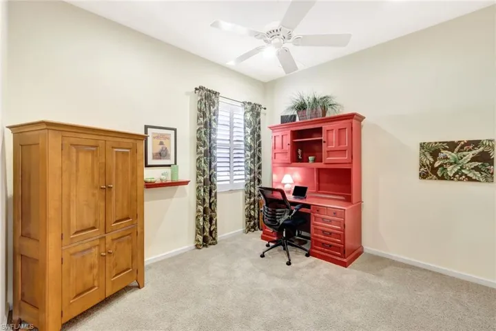 Carpeted home office featuring ceiling fan