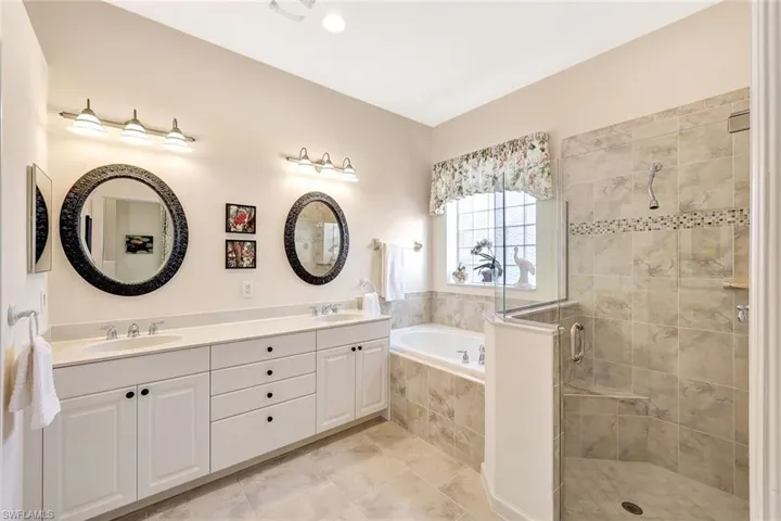 Bathroom featuring tile patterned flooring, shower with separate bathtub, and vanity