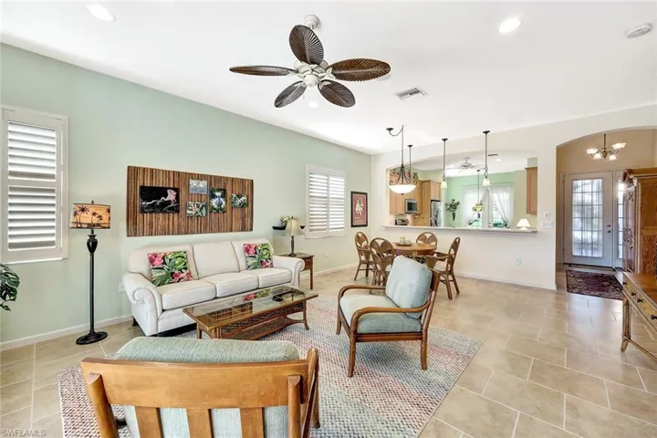 Living room featuring ceiling fan with notable chandelier and light tile patterned flooring