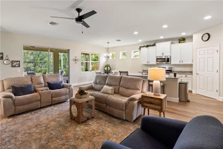 Living area featuring light wood finished floors, recessed lighting, a chandelier, and a ceiling fan
