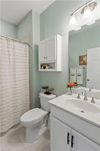 Full bathroom featuring a shower with shower curtain, vanity, and light tile patterned floors