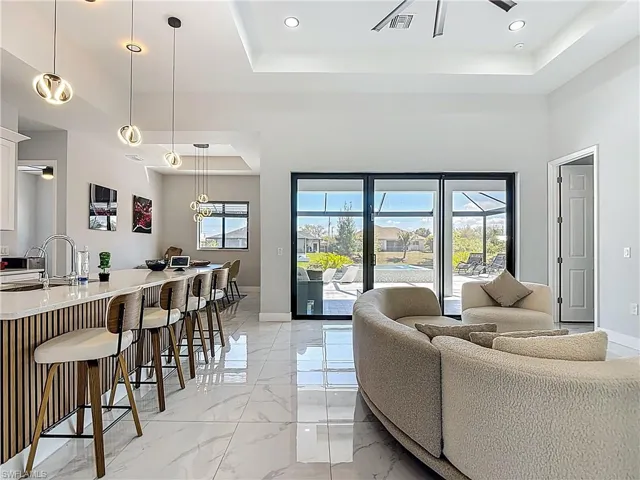 Living room featuring light marble finish flooring, recessed lighting, and a raised ceiling
