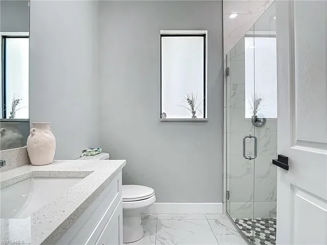 Full bathroom with vanity, a marble finish shower, and light marble finish floors
