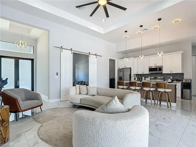 Living area featuring a barn door, ceiling fan, a high ceiling, recessed lighting, and french doors