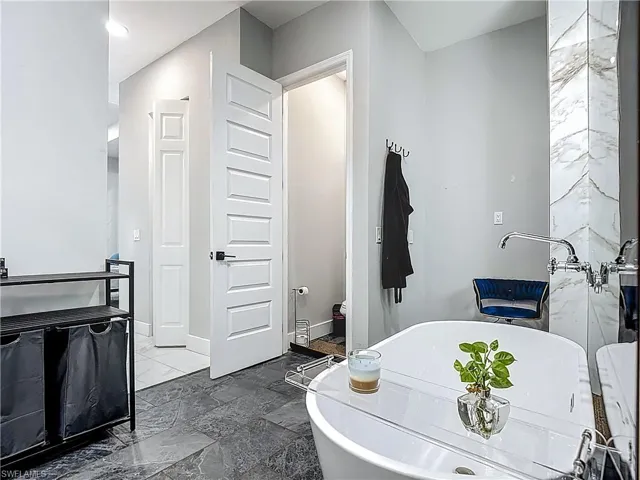 Full bathroom with stone tile flooring, a soaking tub, and vanity