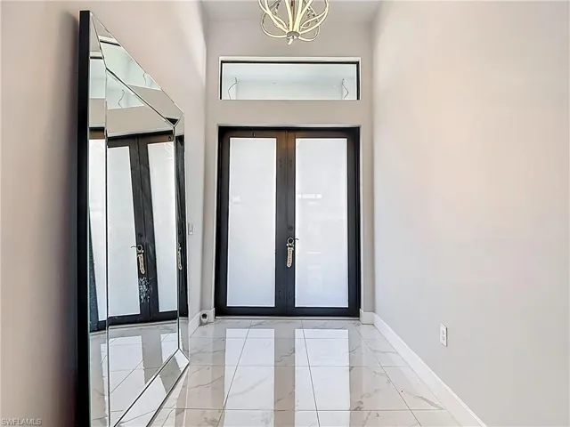 Foyer featuring french doors, hanging lights, and light marble finish floors