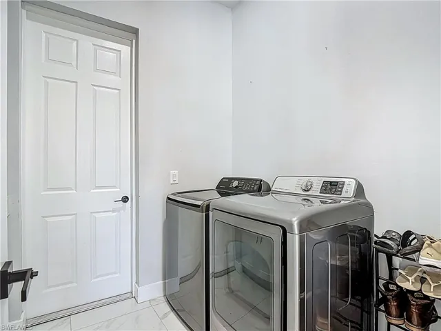 Laundry room featuring light marble finish floors and washing machine and dryer