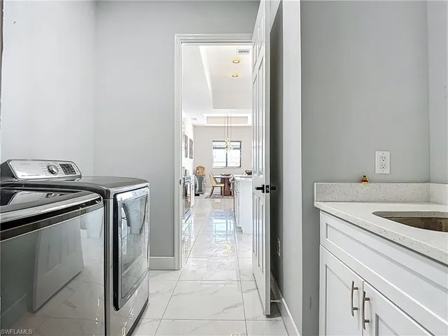 Laundry area with washing machine and clothes dryer and light marble finish flooring