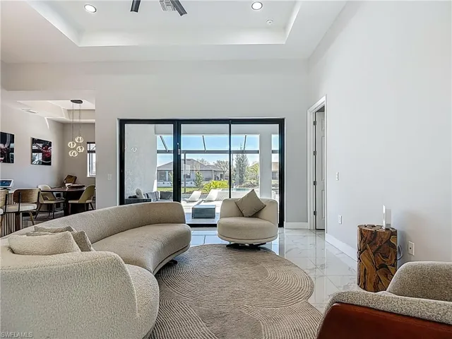 Living area with light marble finish floors, recessed lighting, and a raised ceiling