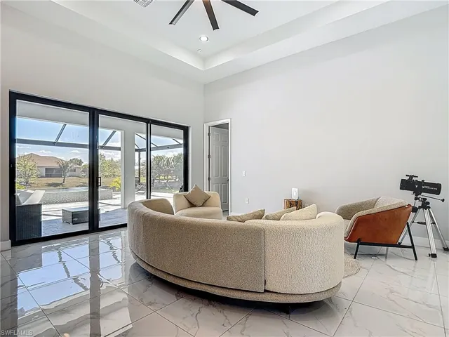 Living area featuring ceiling fan, a high ceiling, light marble finish flooring, and recessed lighting