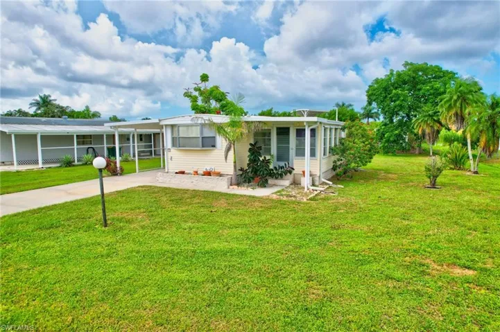 Rear view of house featuring a carport, driveway, and a yard