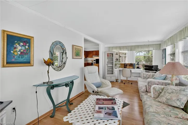 Living area with an office area, ornamental molding, and light wood-type flooring