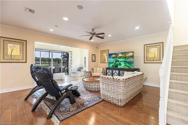 Living room featuring ceiling fan, wood-type flooring, and ornamental molding