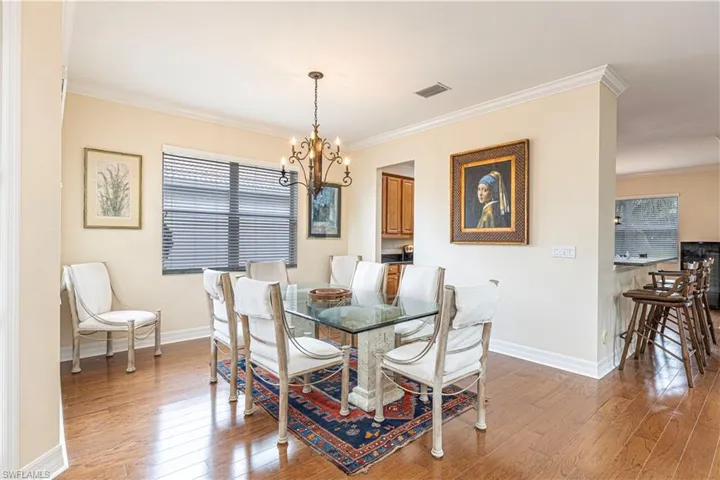 Dining area featuring an inviting chandelier, crown molding, and hardwood / wood-style floors