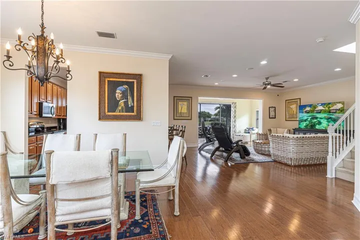 Dining room with ceiling fan with notable chandelier, hardwood / wood-style floors, and ornamental molding
