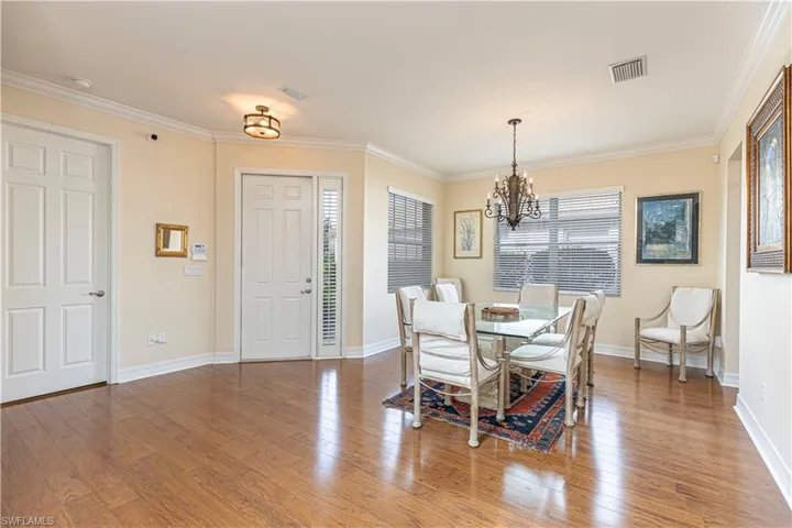 Dining area featuring hardwood / wood-style flooring, a notable chandelier, and ornamental molding
