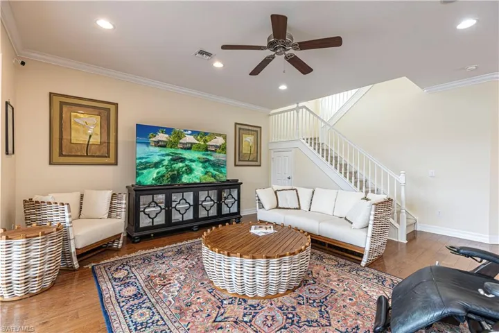 Living room featuring hardwood / wood-style flooring, ornamental molding, and ceiling fan