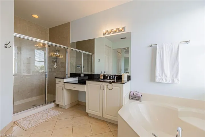 Bathroom featuring plus walk in shower, vanity, and tile patterned floors