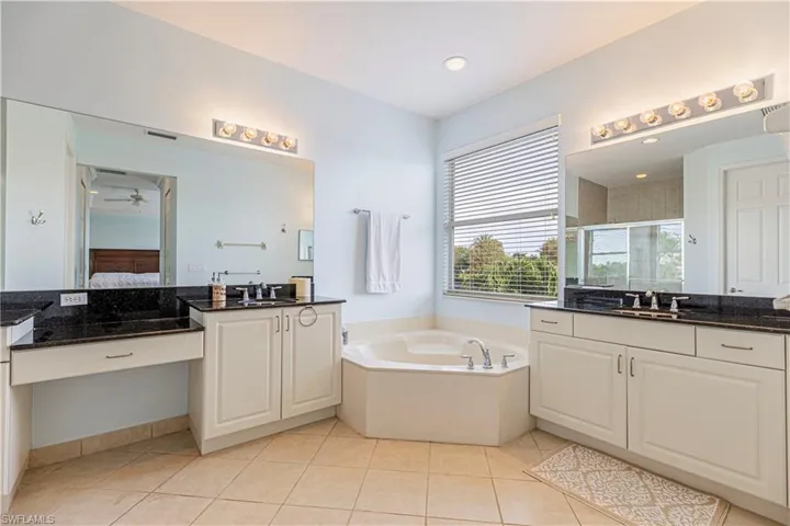 Bathroom with ceiling fan, a washtub, tile patterned flooring, and double vanity