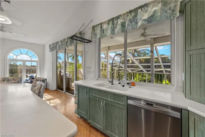 Kitchen featuring sink, green cabinets, light hardwood / wood-style floors, dishwasher, and ceiling fan