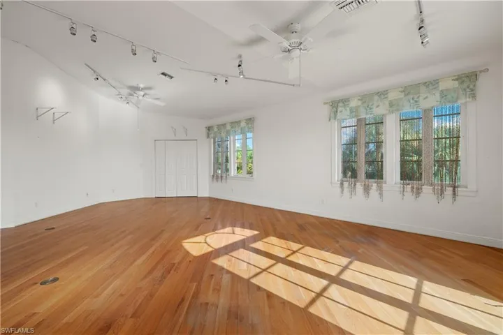 Spare room featuring ceiling fan, light hardwood / wood-style floors, rail lighting, and vaulted ceiling