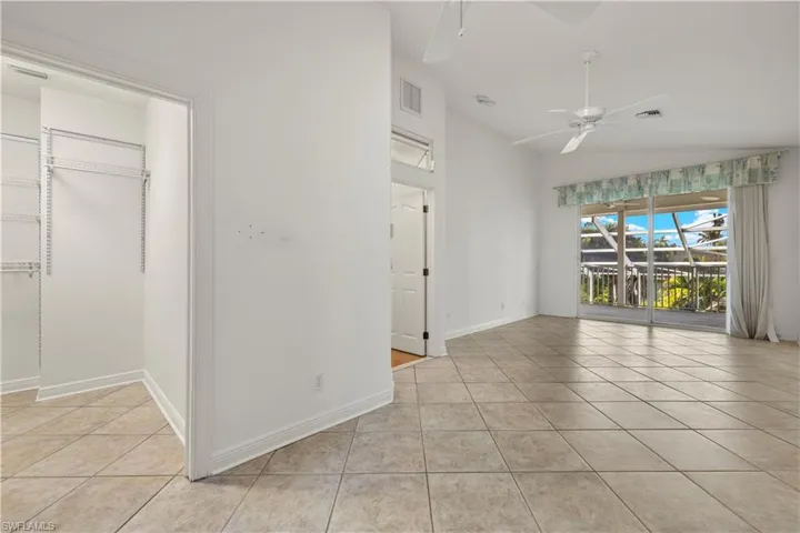 Tiled empty room with ceiling fan and lofted ceiling