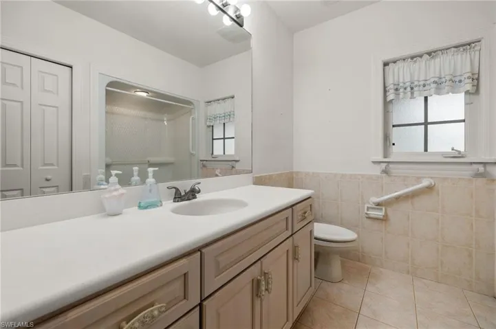 Bathroom featuring tile patterned flooring, tile walls, a wealth of natural light, and vanity