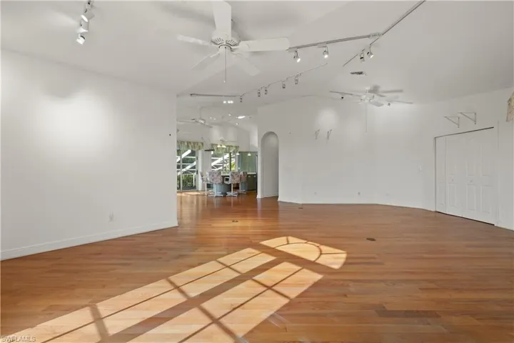 Empty room with ceiling fan, lofted ceiling, rail lighting, and light wood-type flooring