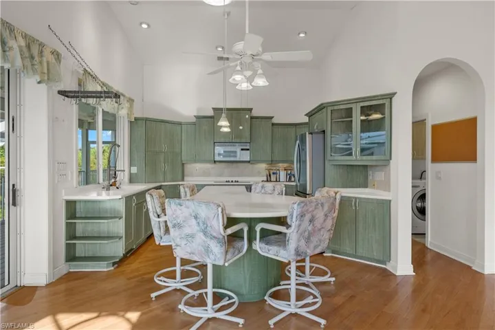 Kitchen featuring decorative backsplash, light wood-type flooring, washer / dryer, green cabinets, and stainless steel fridge