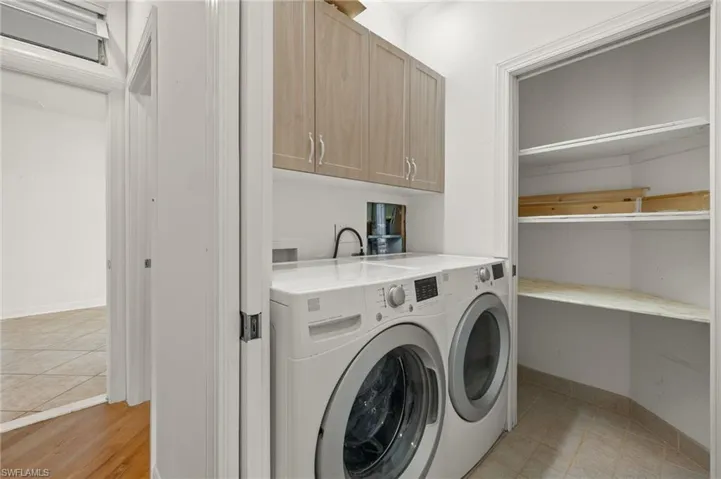 Clothes washing area with light hardwood / wood-style floors, washing machine and dryer, and cabinets