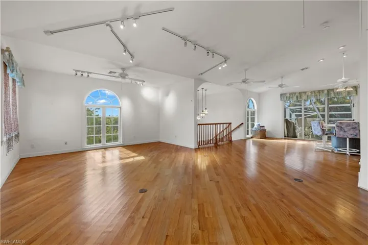 Unfurnished living room featuring ceiling fan, track lighting, and light hardwood / wood-style flooring