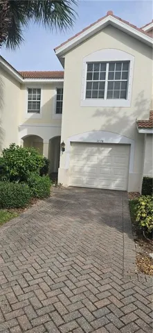 View of front facade with stucco siding, decorative driveway, and an attached garage