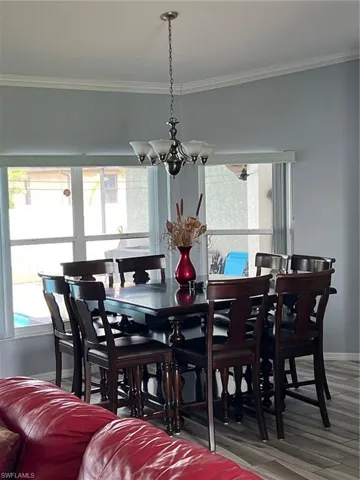 Dining space featuring crown molding, a chandelier, and wood finished floors