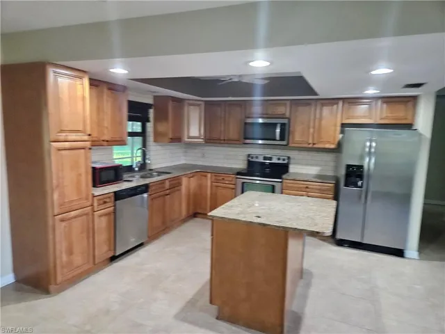 Kitchen featuring stainless steel appliances, tasteful backsplash, recessed lighting, a kitchen island, and brown cabinets