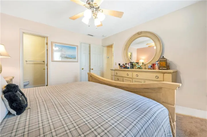 Carpeted bedroom featuring ceiling fan and ensuite bathroom