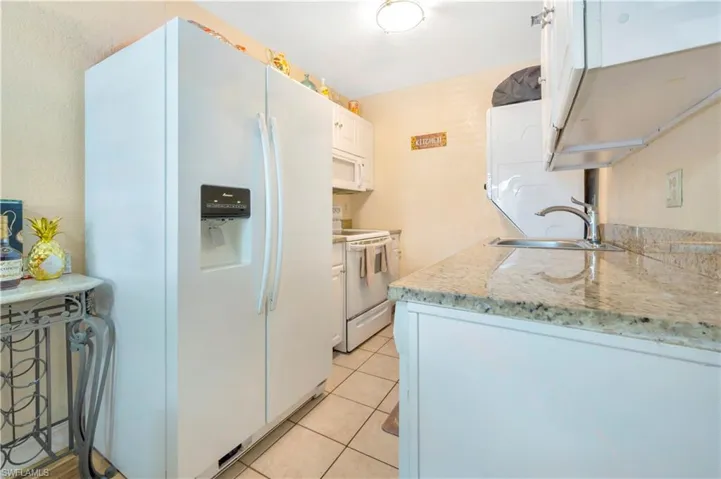 Kitchen featuring light stone countertops, white appliances